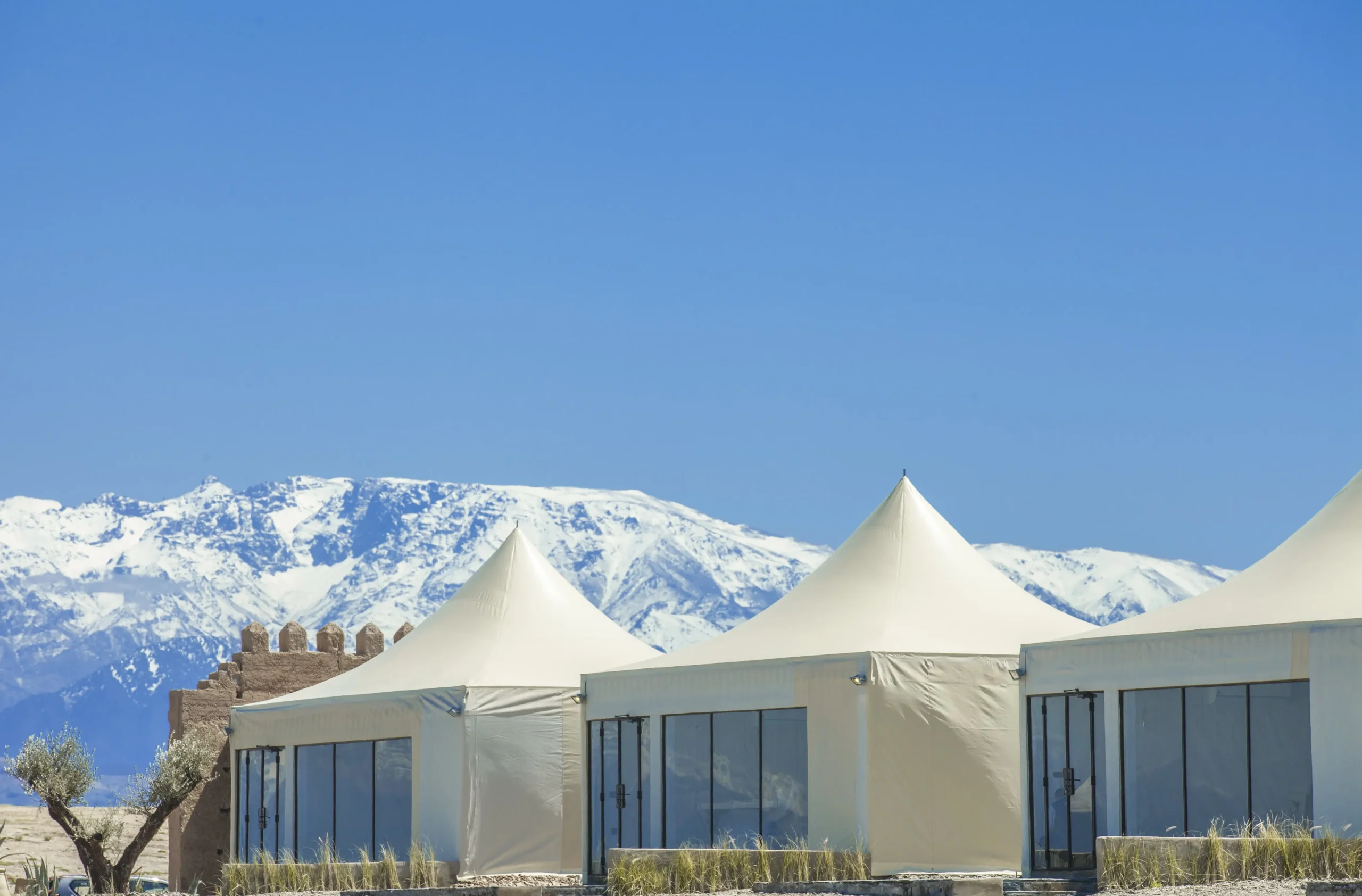 Sunset view of The White Camel agafay luxury camp with Atlas Mountains backdrop